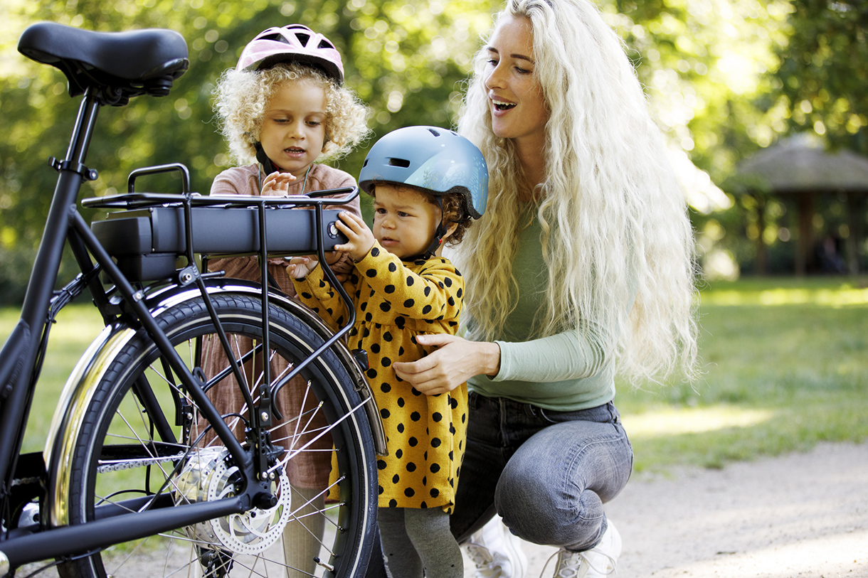 Mother checking battery on electric bicycle with daughters