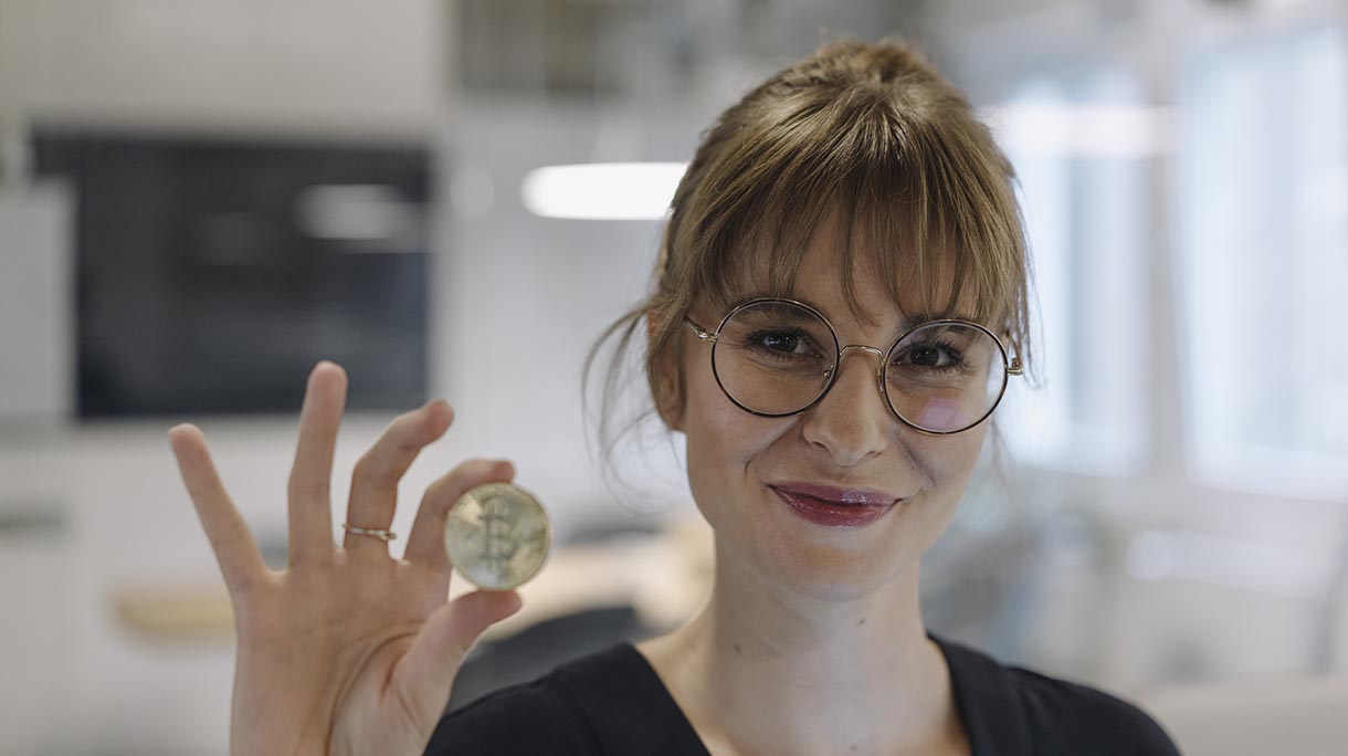 Portrait of businesswoman holding bitcoin in office