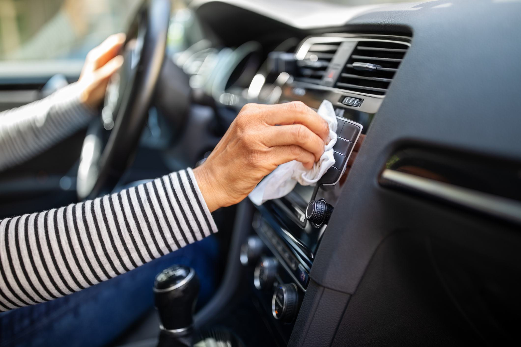 Female hands cleaning and disinfecting her car interior