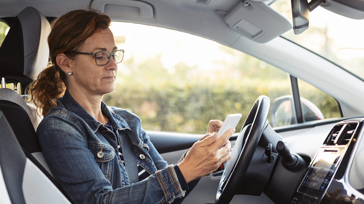 Mature woman texting while sitting in car