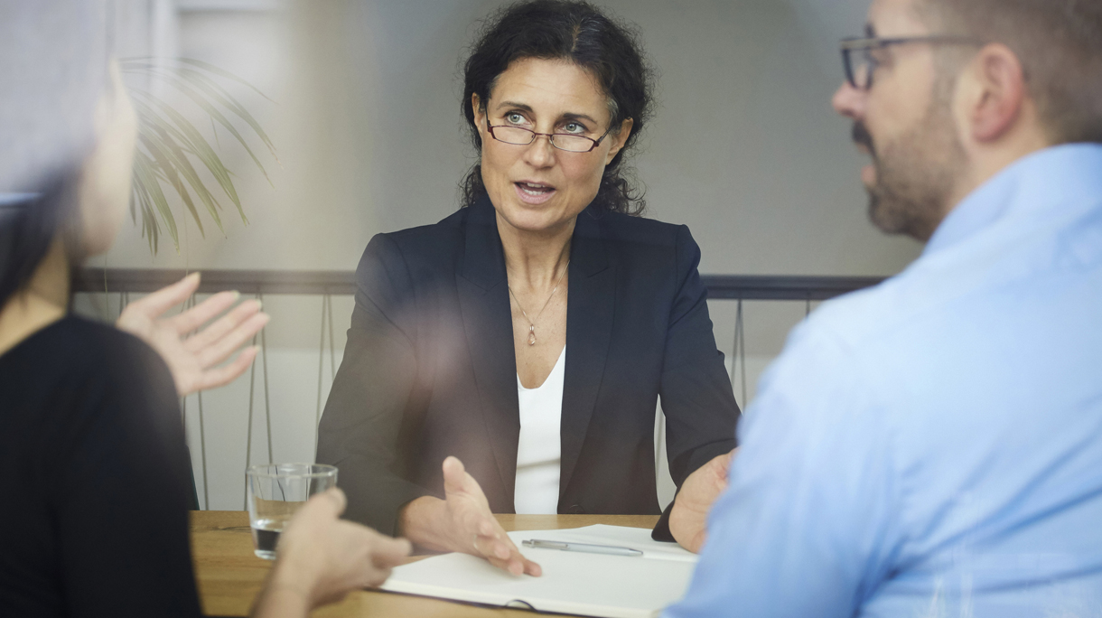 Confident mature female lawyer discussing with businessman and businesswoman during meeting at office