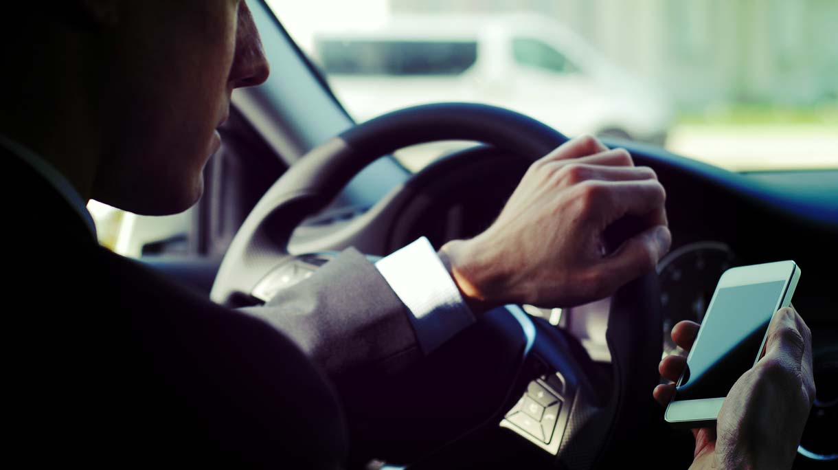 Businessman texting while driving a car