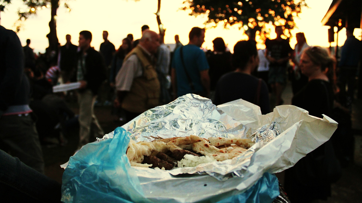 Close-Up Of Cevapcici Against People In Event At Yard