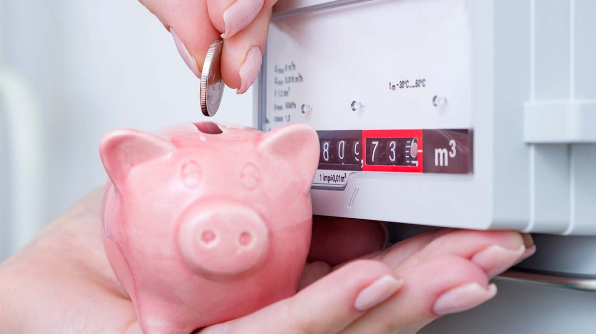 Woman puts coin in piggy bank near a gas meter. Saving natural gas and energy efficiency at home, concept image.