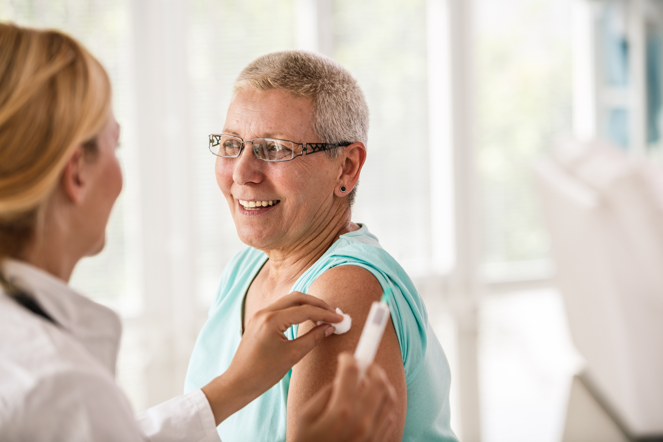 Doctor disinfecting patient’s arm before vaccination