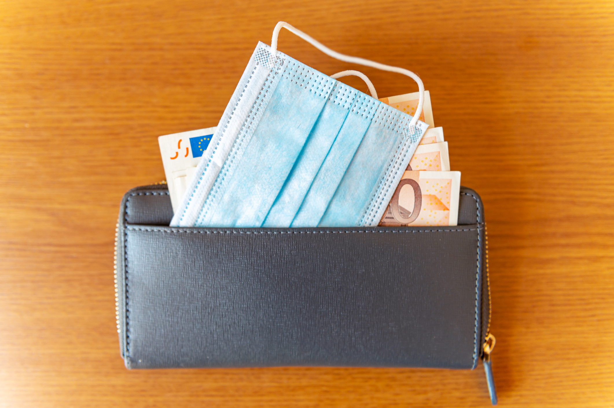 Disposable medical mask near money bills in wallet