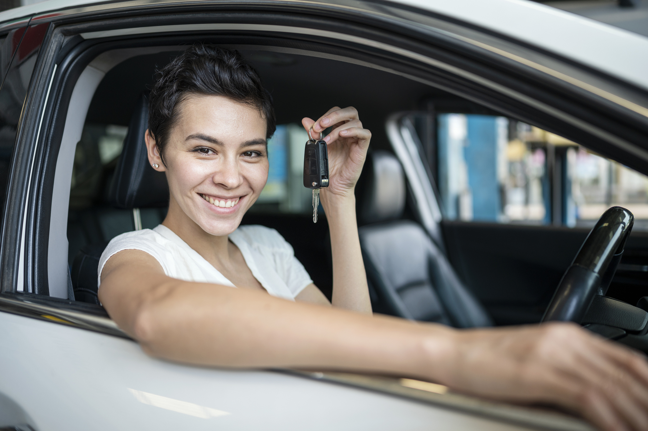 A Happy women customer holding a car key in the Auto Repair shop testing car after repairing complete.