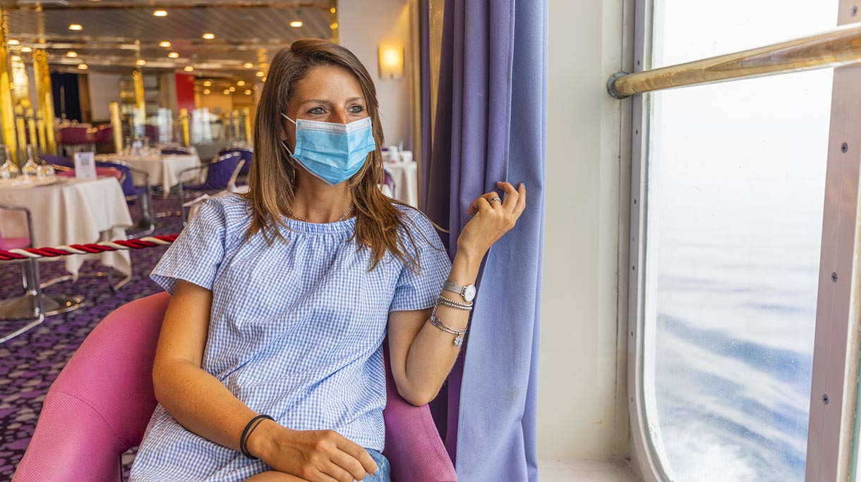 Young woman wearing a protective face mask to travel safely on a cruise ship, Mediterranean sea, Italy