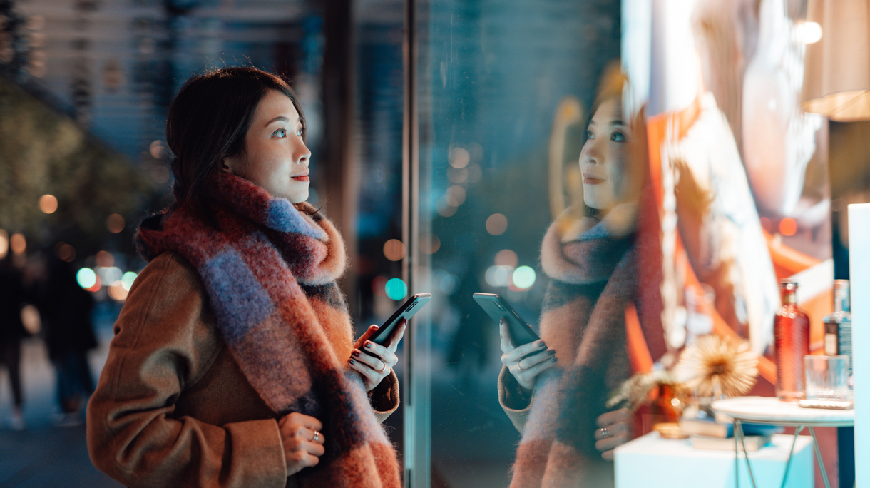 Young woman window shopping in the city at night
