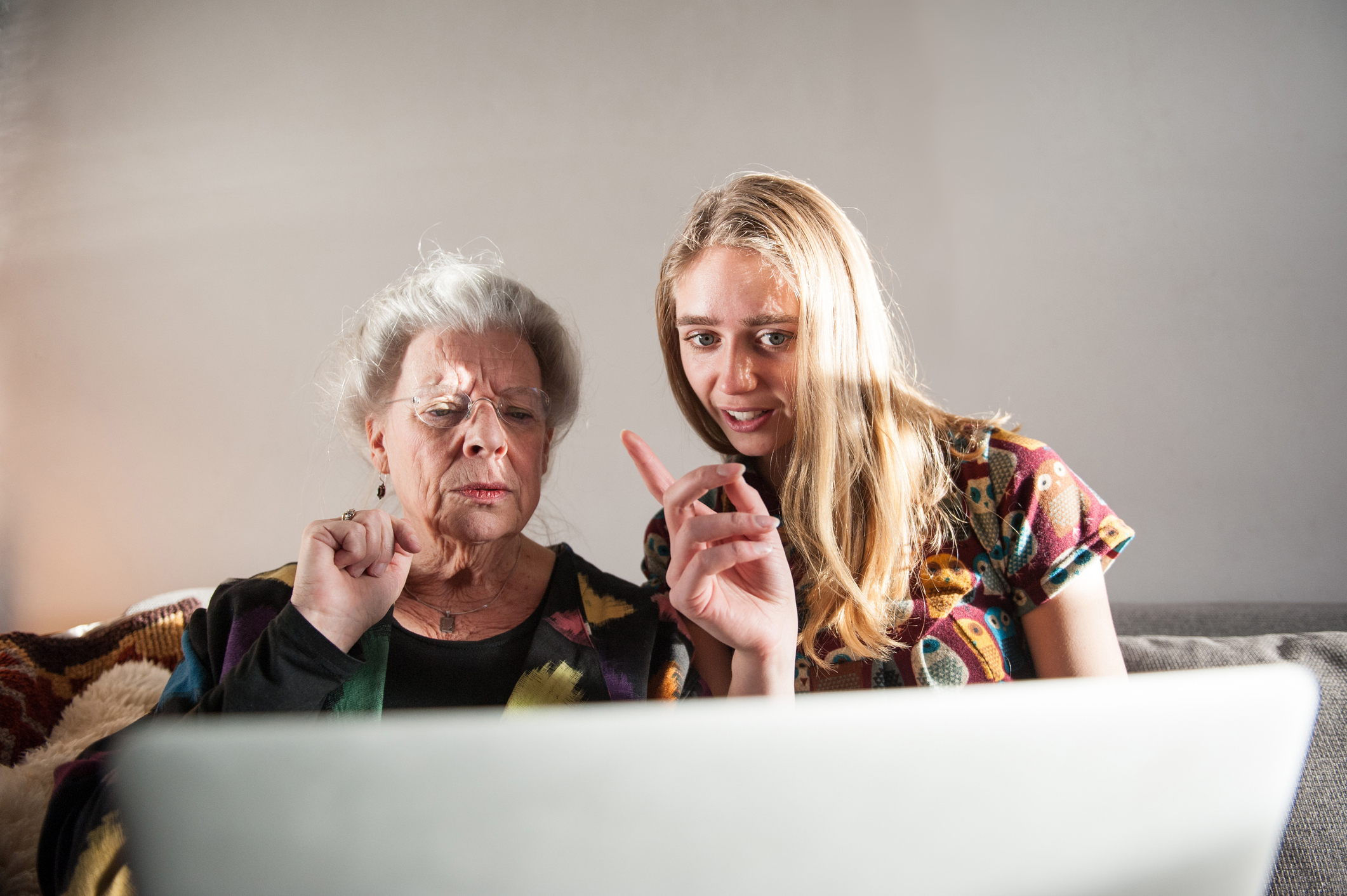 Young woman showing senior lady how to work laptop