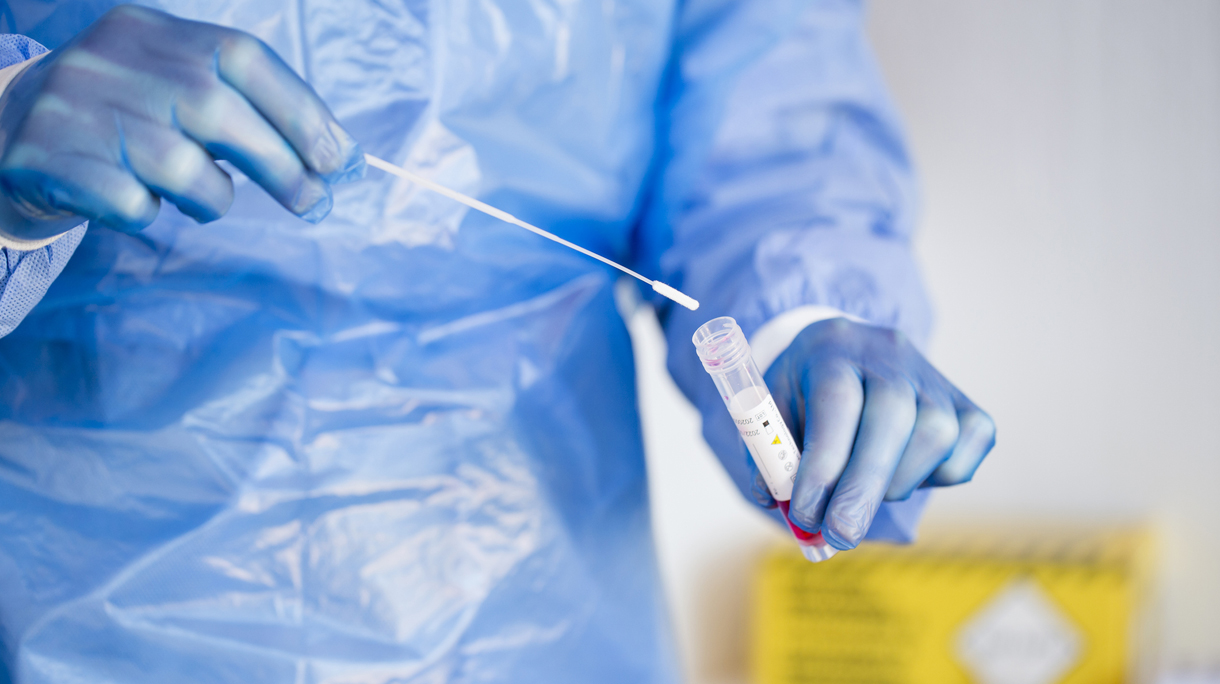 Close-up of a doctor putting a PCR test swab into a tube