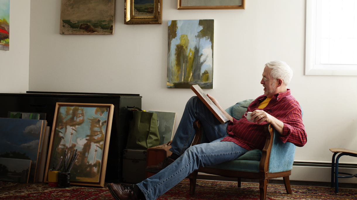Man looking at painting while sitting on armchair