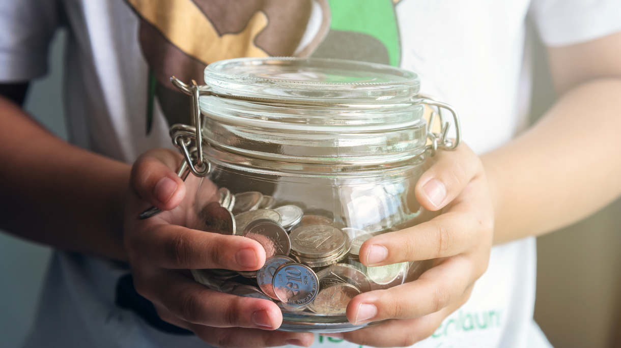 Young Child Holding Coins Jar