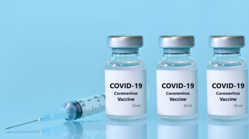 Three vials with a vaccine, a syringe on a blue background.The concept of medicine, healthcare and science.Coronavirus vaccine.Copy space for text..Banner