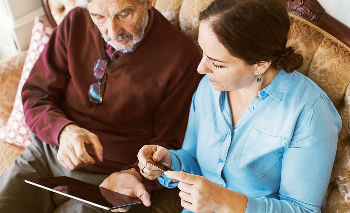Senior man doing online shopping with daughter through credit card and digital tablet