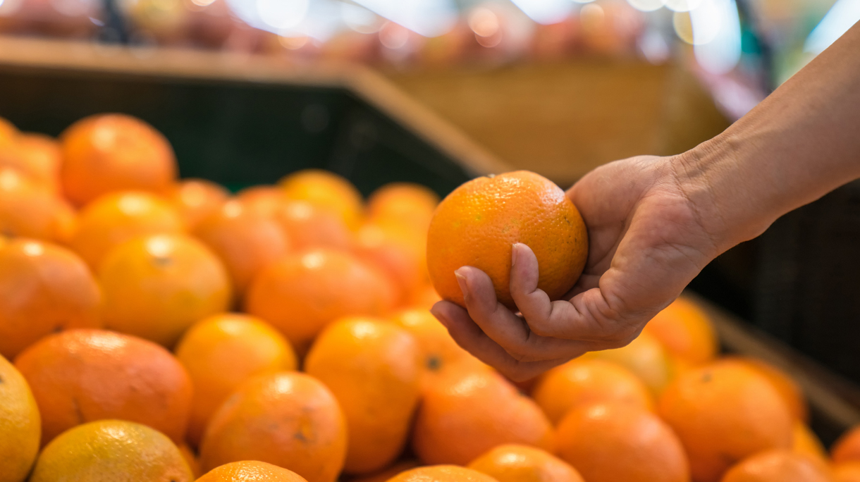 Man chooses oranges in the supermarket.