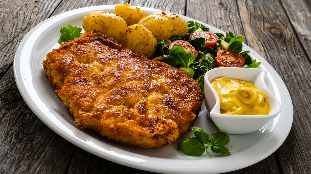 Fried pork chop and vegetable salad on wooden table
