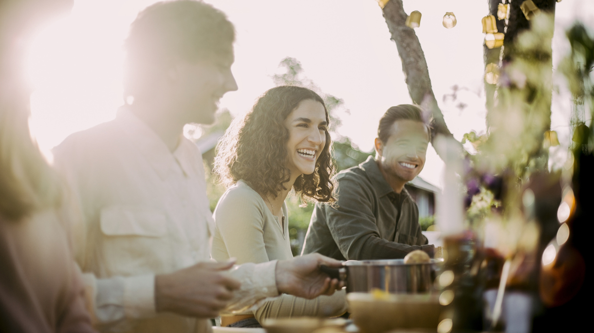 Cheerful female with friends sitting in backyard at garden party