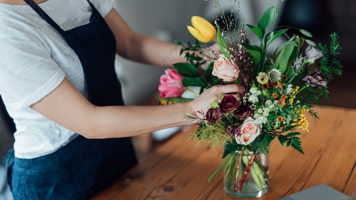 Cropped shot of young woman arranging fresh flowers at home