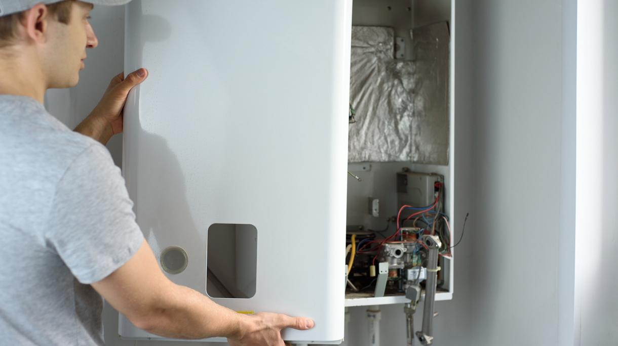 A man checks a gas boiler for home heating. Maintenance and repair of gas heating