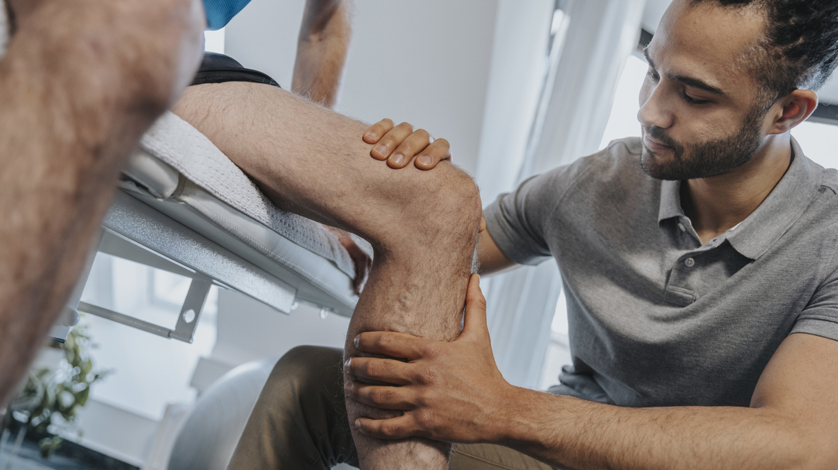 Male Physical therapist examining knee of patient in practice