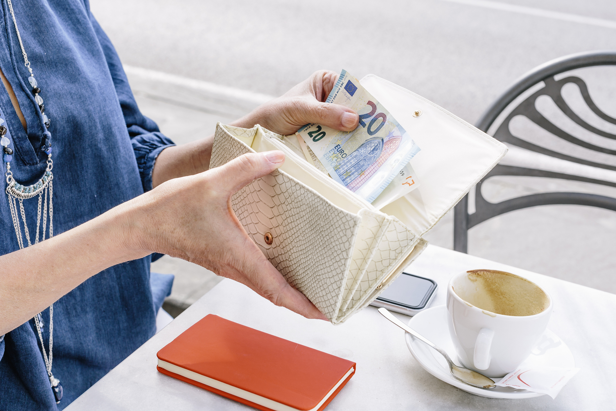 Hand of mature woman removing euro note from purse at sidewalk cafe, Fiesole, Tuscany, Italy