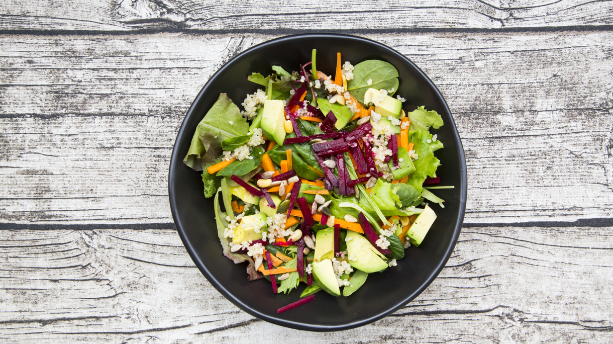 Bowl of autumnal salad with lettuce, carrots, avocado, beetroot, pumpkin and sunflower seeds, pomegranate and quinoa