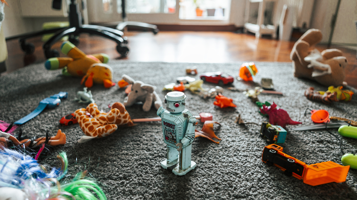 toy robot surrounded by other toys on the carpet in child bedroom