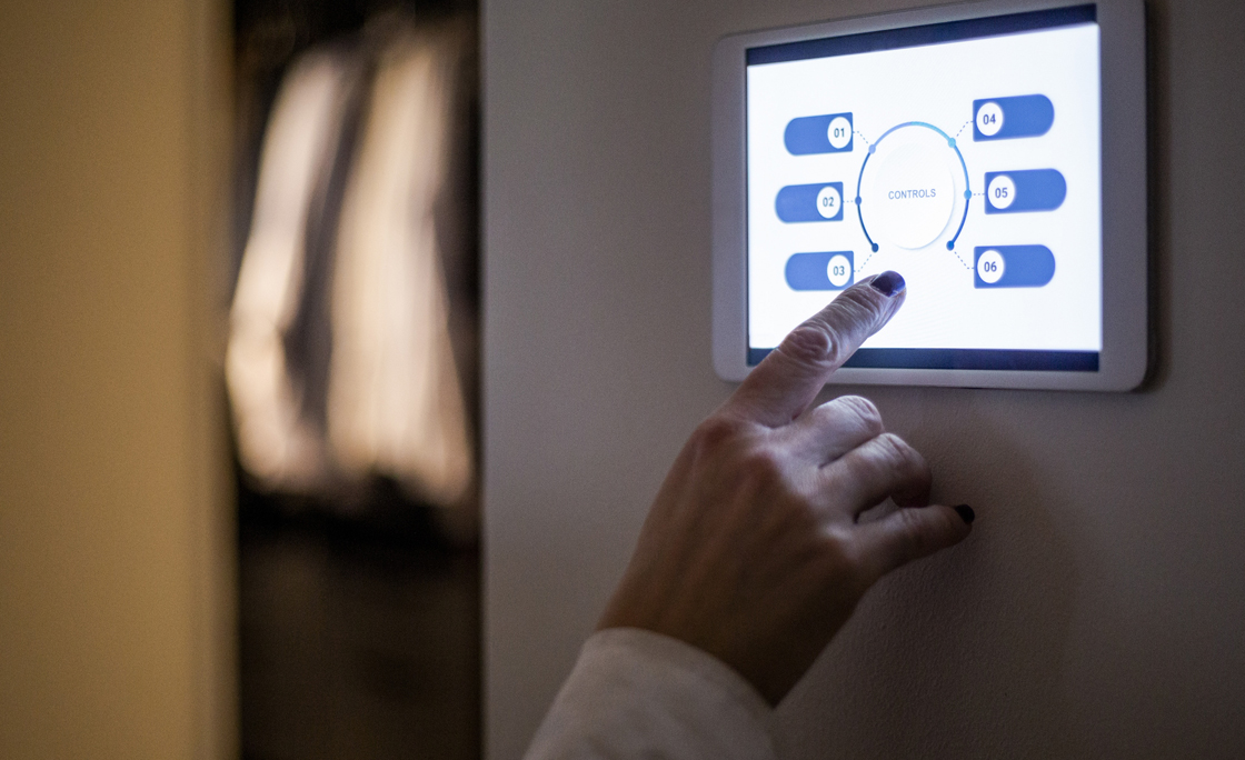 Cropped hand of woman using digital tablet mounted on wall at home
