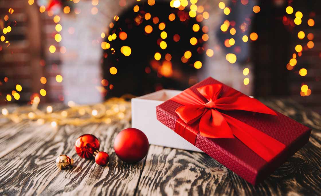 Gift boxes with a large red bow  against a background bokeh of twinkling party lights. Luxury New Year gift. Christmas gift. Christmas background with gift box. Christmastime celebration