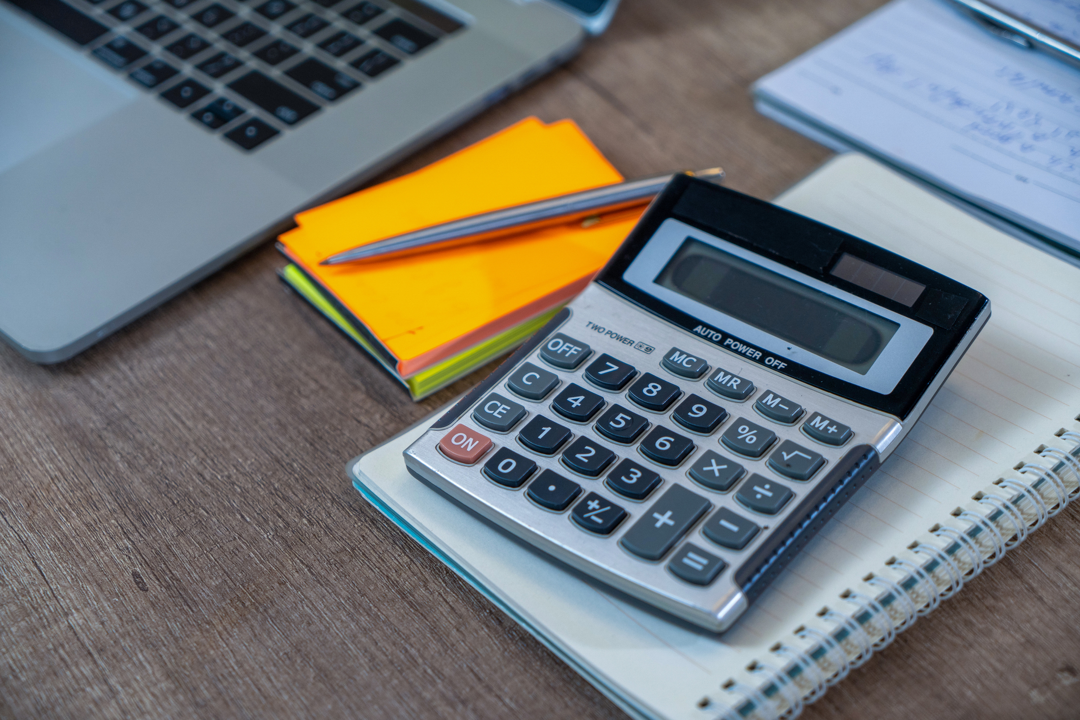 calculator, business document and laptop computer notebook on wooden table