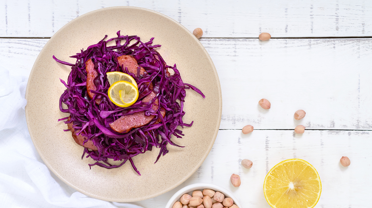 Salad of red cabbage, salami, peanuts on a white wooden background. Top view