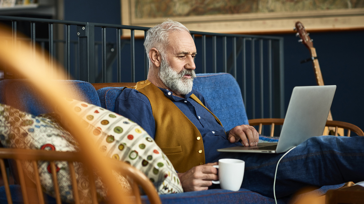 Senior man working on laptop at home with serious expression