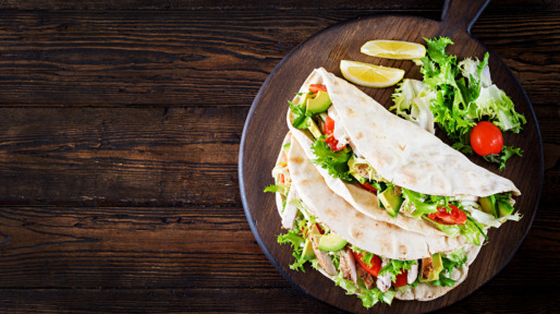 Pita bread sandwiches with grilled chicken meat, avocado, tomato, cucumber and lettuce served on  wooden background. Close up. Top view. Healthy fast food concept.