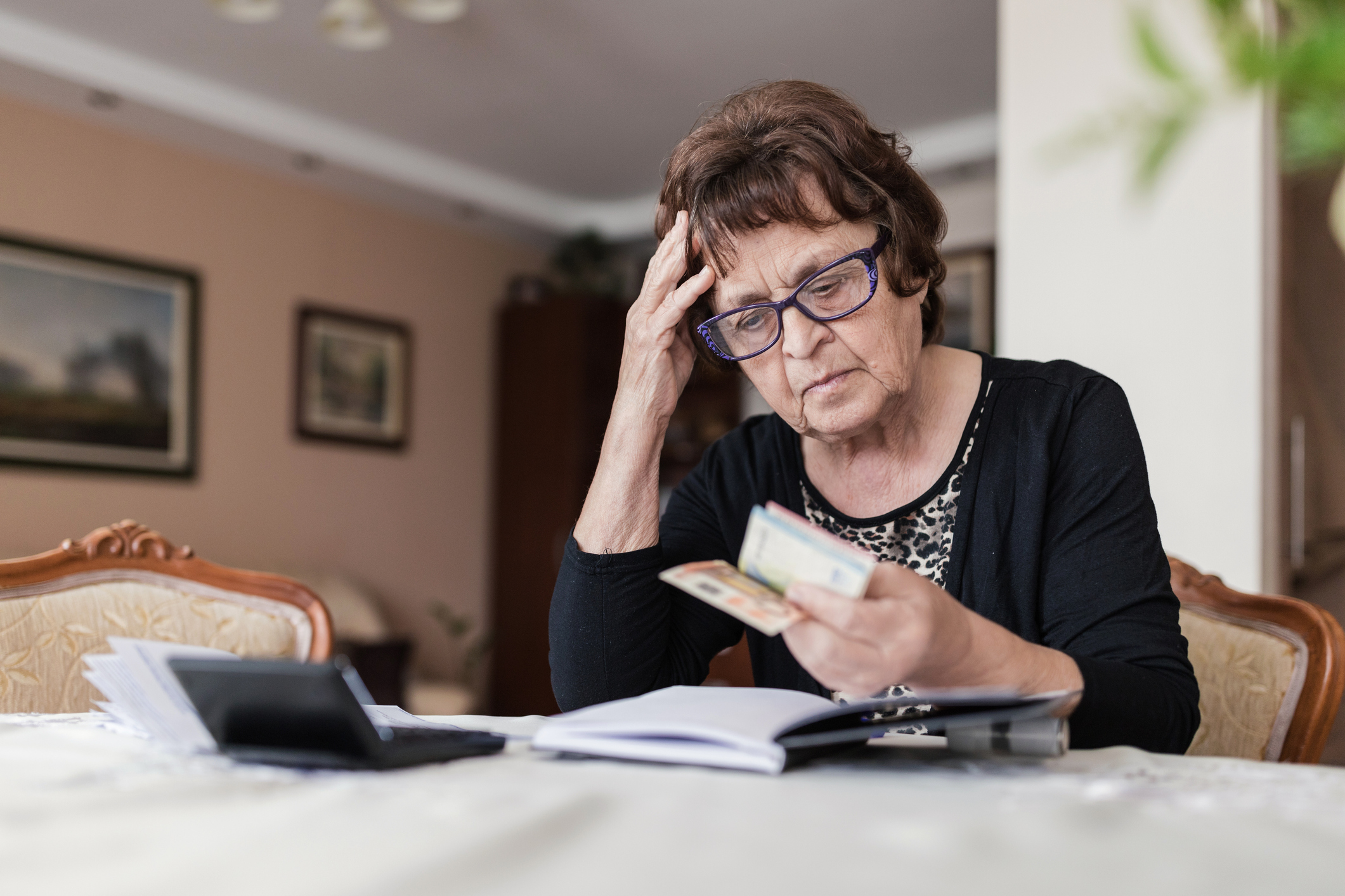 Worried mature woman holding money in hands