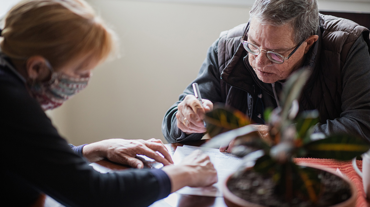 Social worker having a discussion with a senior man to establish what his homecare needs are, in order to make his life as comfortable as possible.
