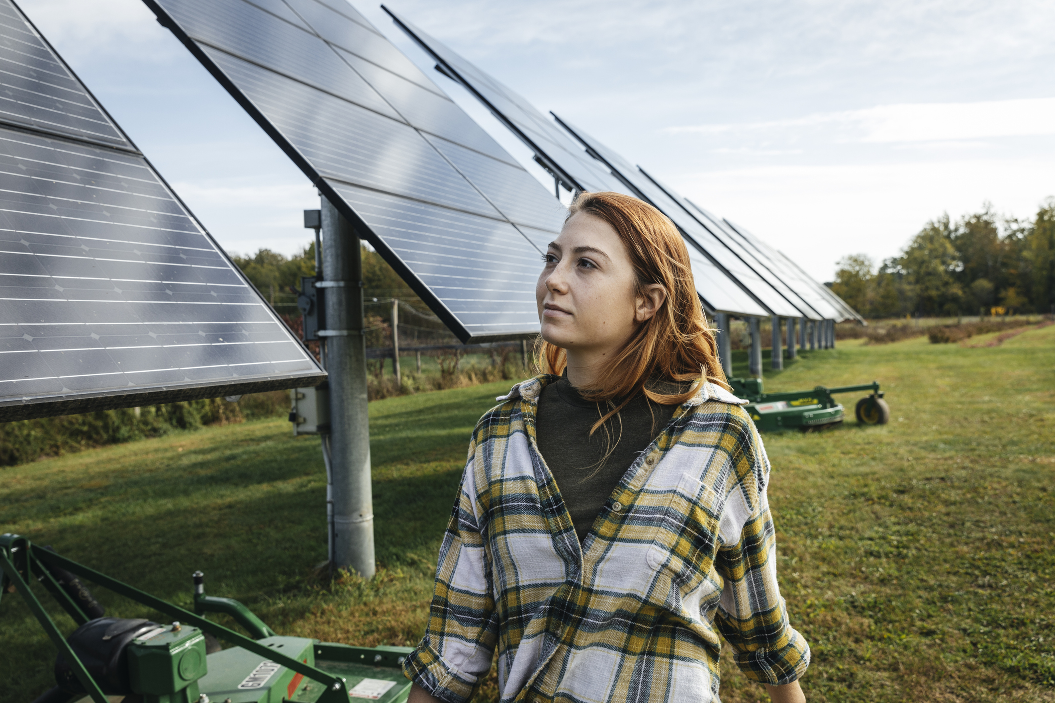 Young woman looking at solar panels on farm
