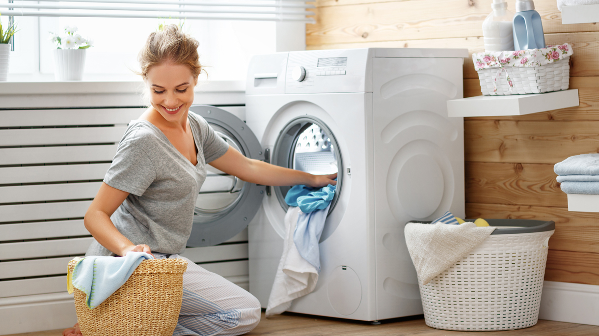 Happy housewife woman in laundry room with washing machine