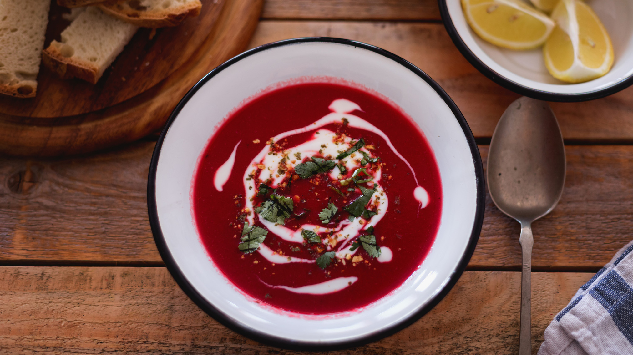 Fresh made beetroot soup with bread slices and lemon served in plate, close-up