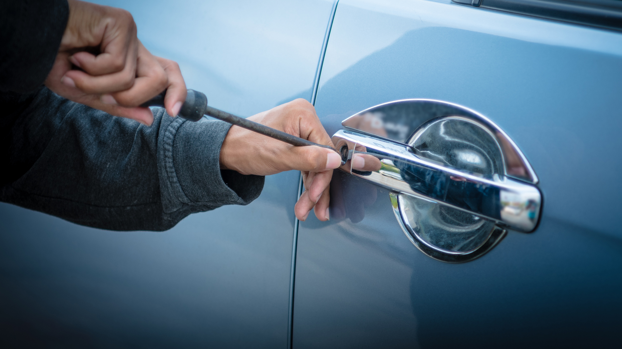 A young man who is breaking into a car
