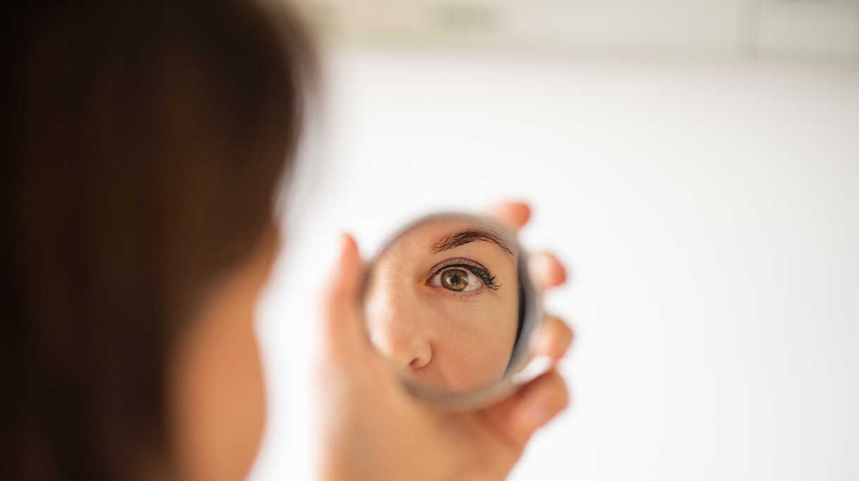 vrouw kijkt in spiegel naar haar ogen