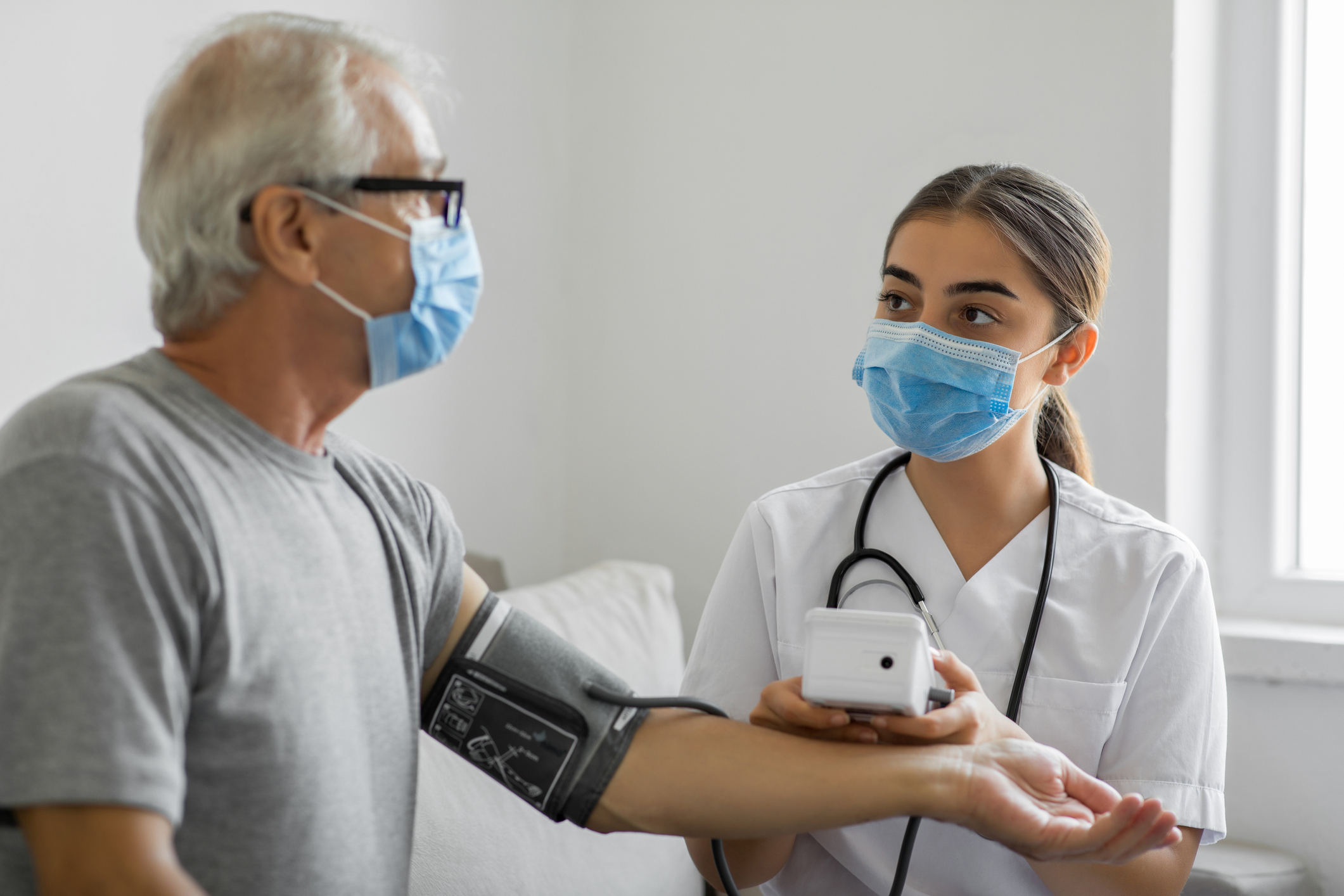 Healthcare worker attends to a senior man in a home