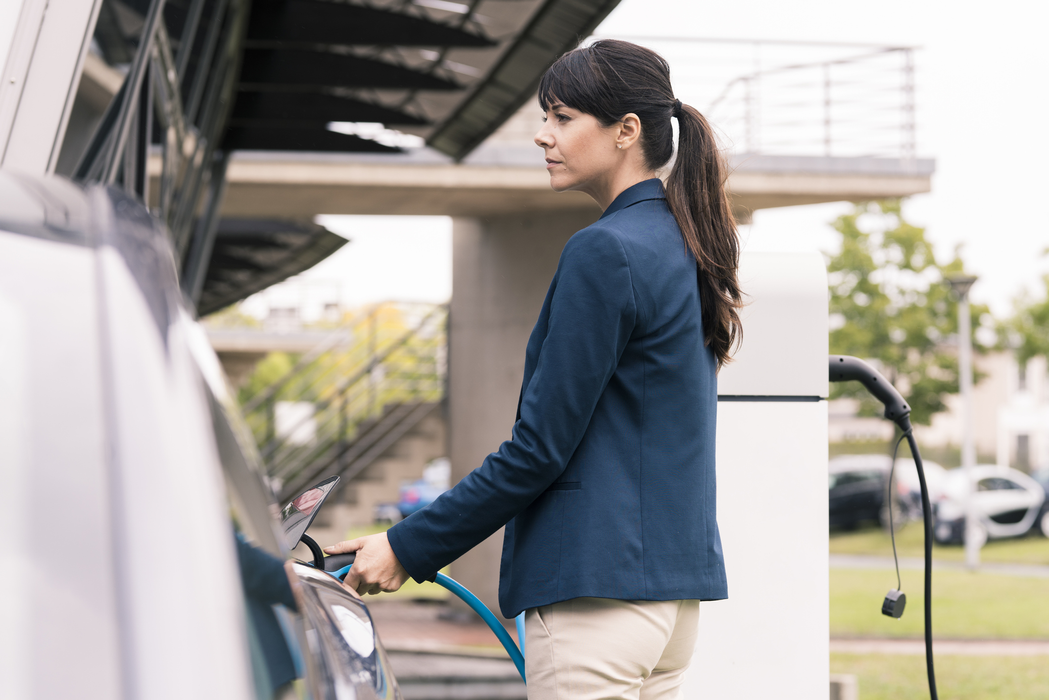 Female professional charging electric car at station