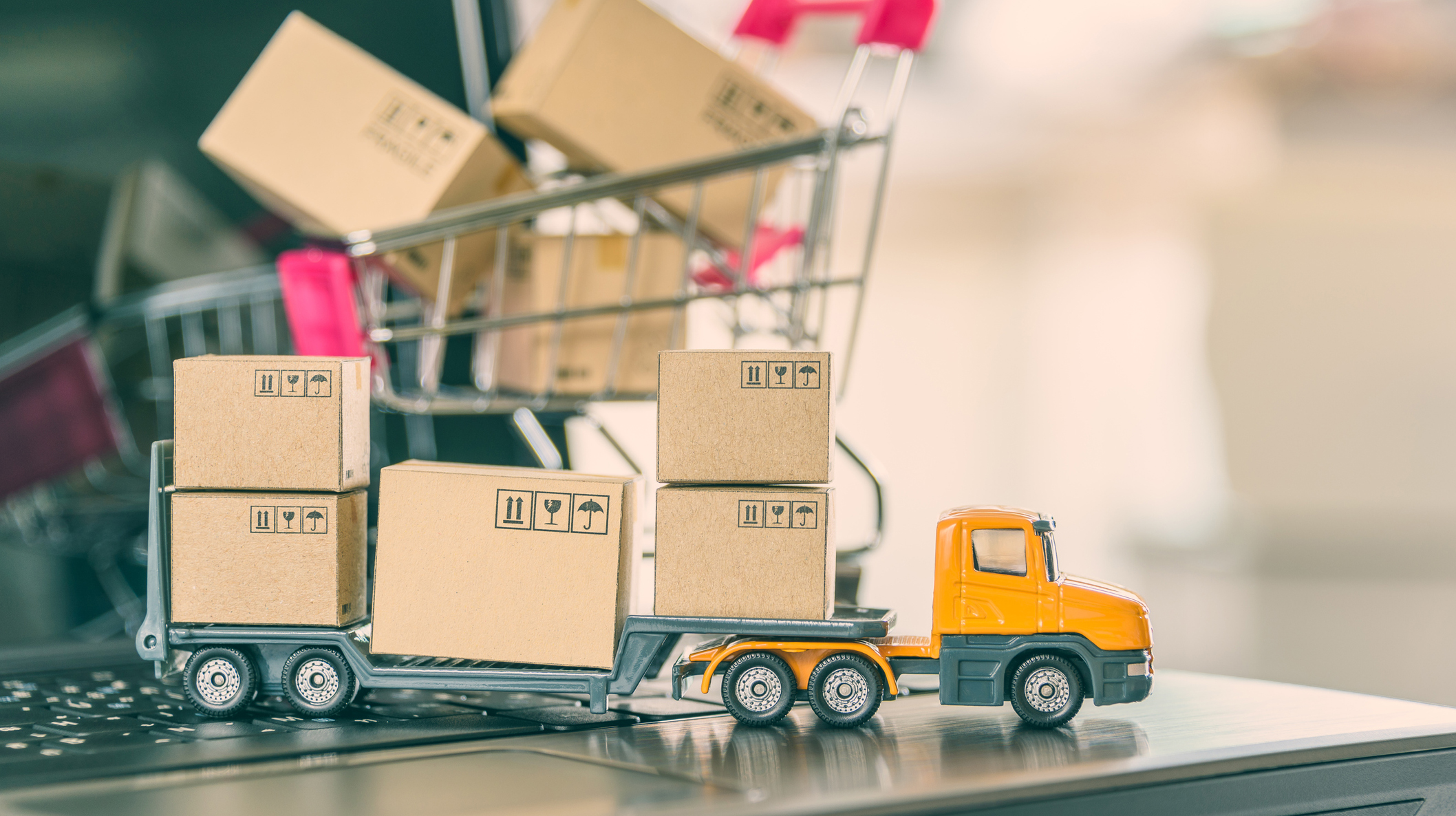 Trailer truck moves boxes of goods or cartons, a shopping cart on a laptop computer