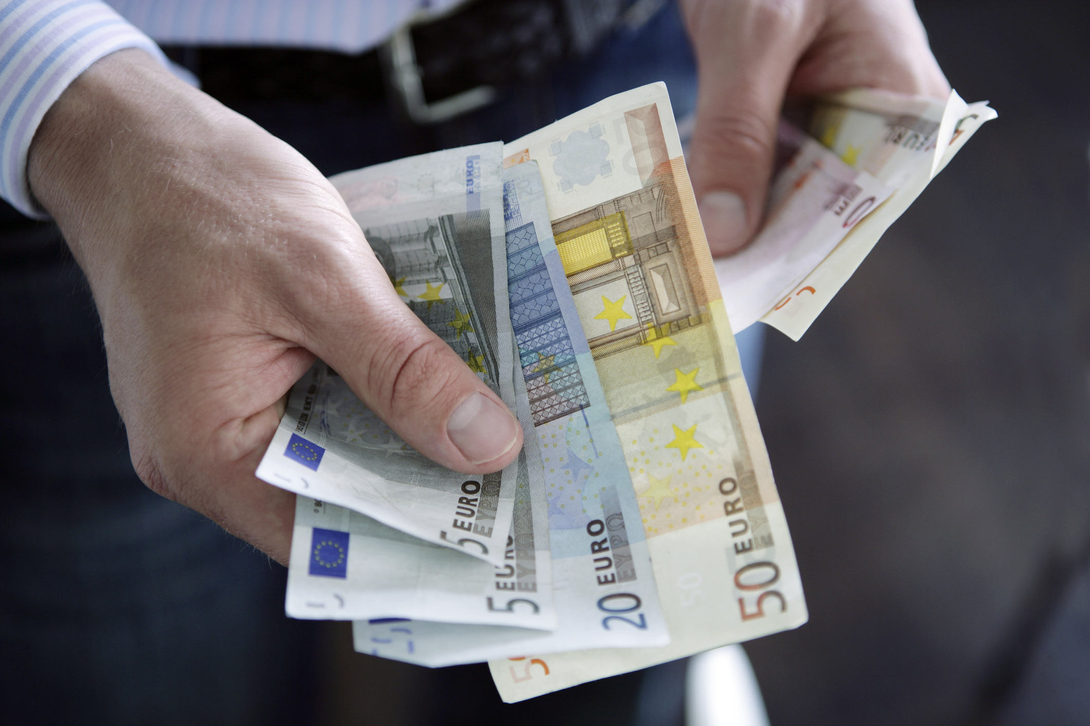 Man holding Euro currency: various denomination notes