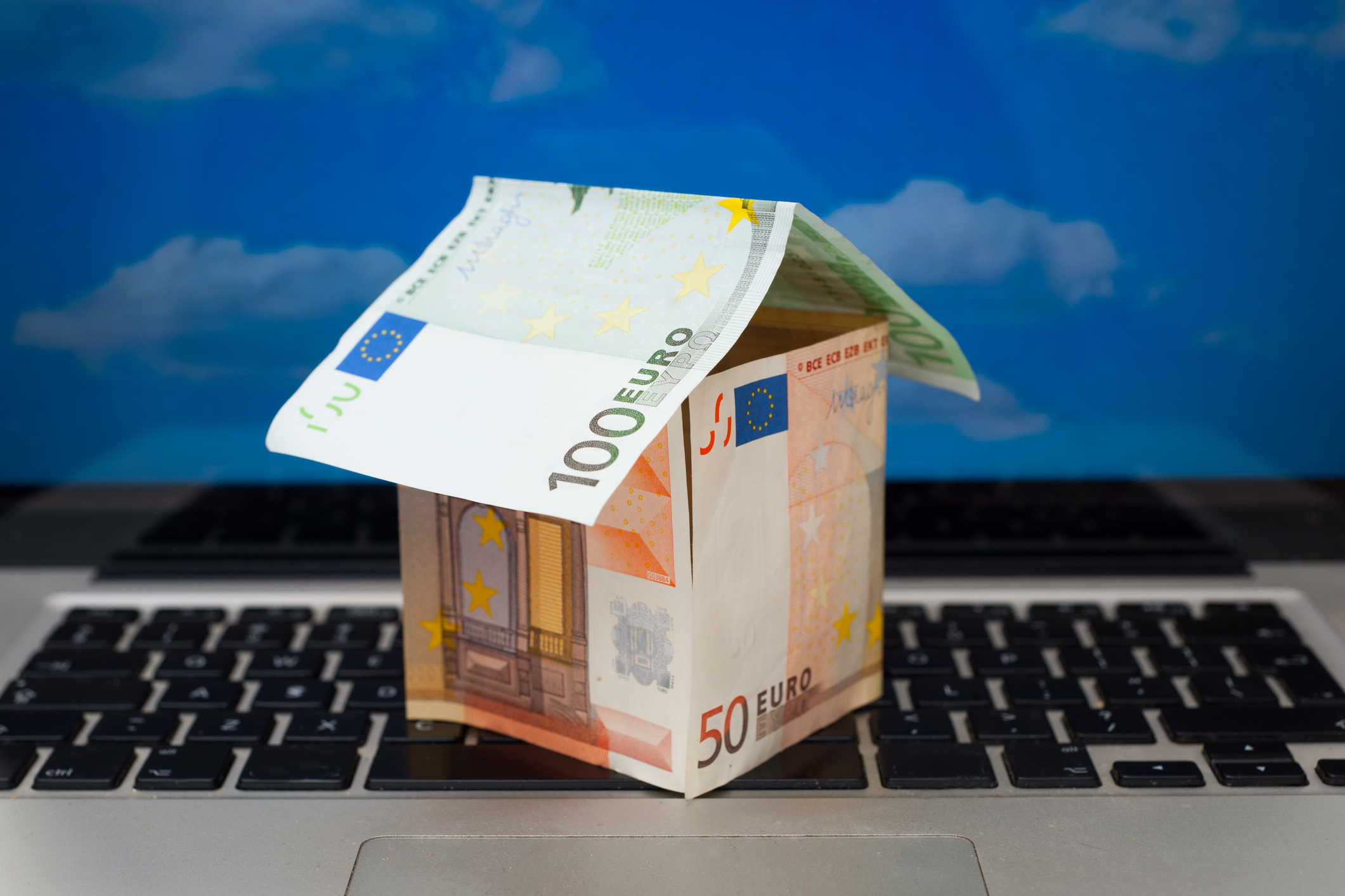 Little house made from euro notes on the laptop