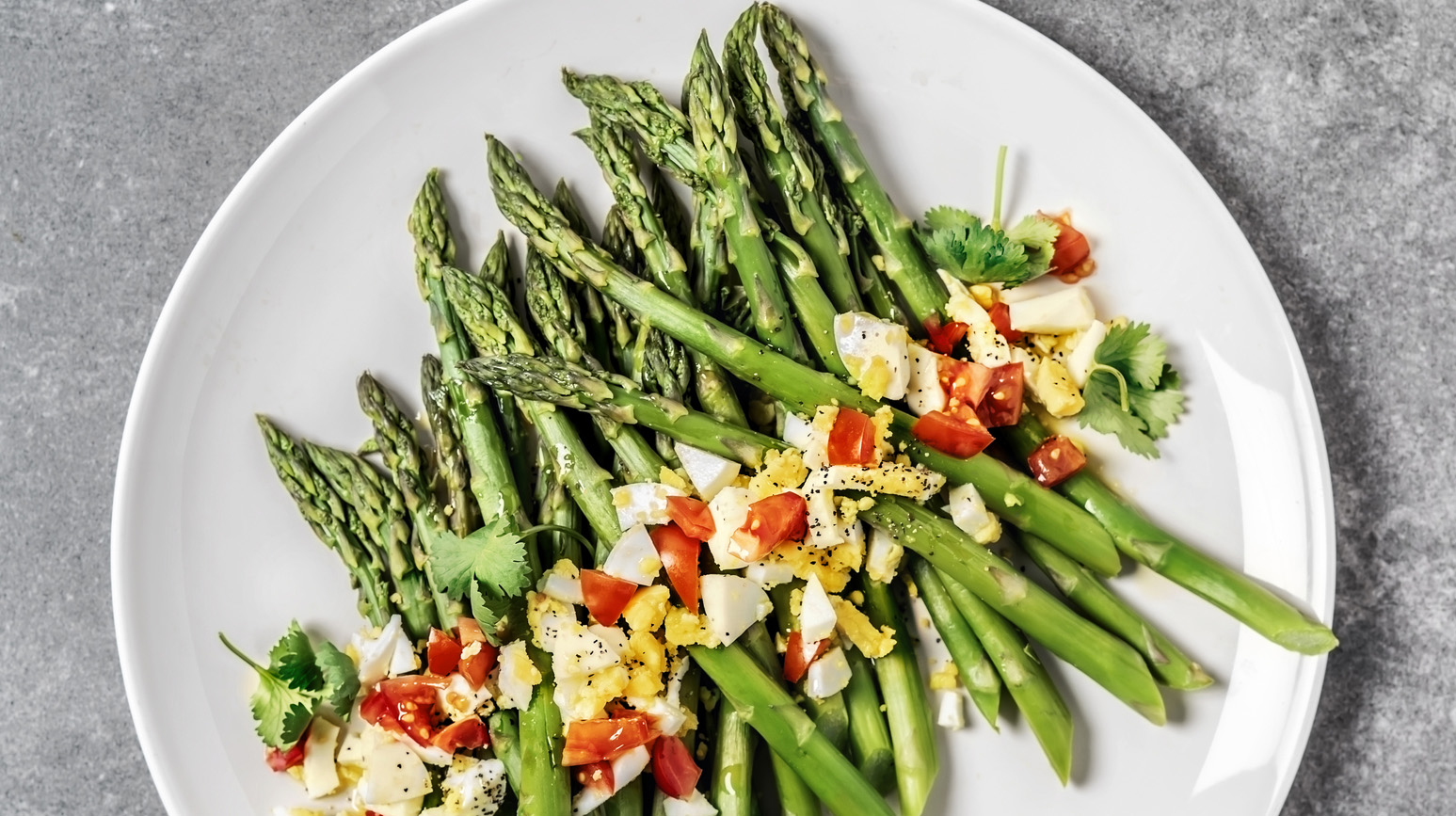A plate of asparagus salad on gray background