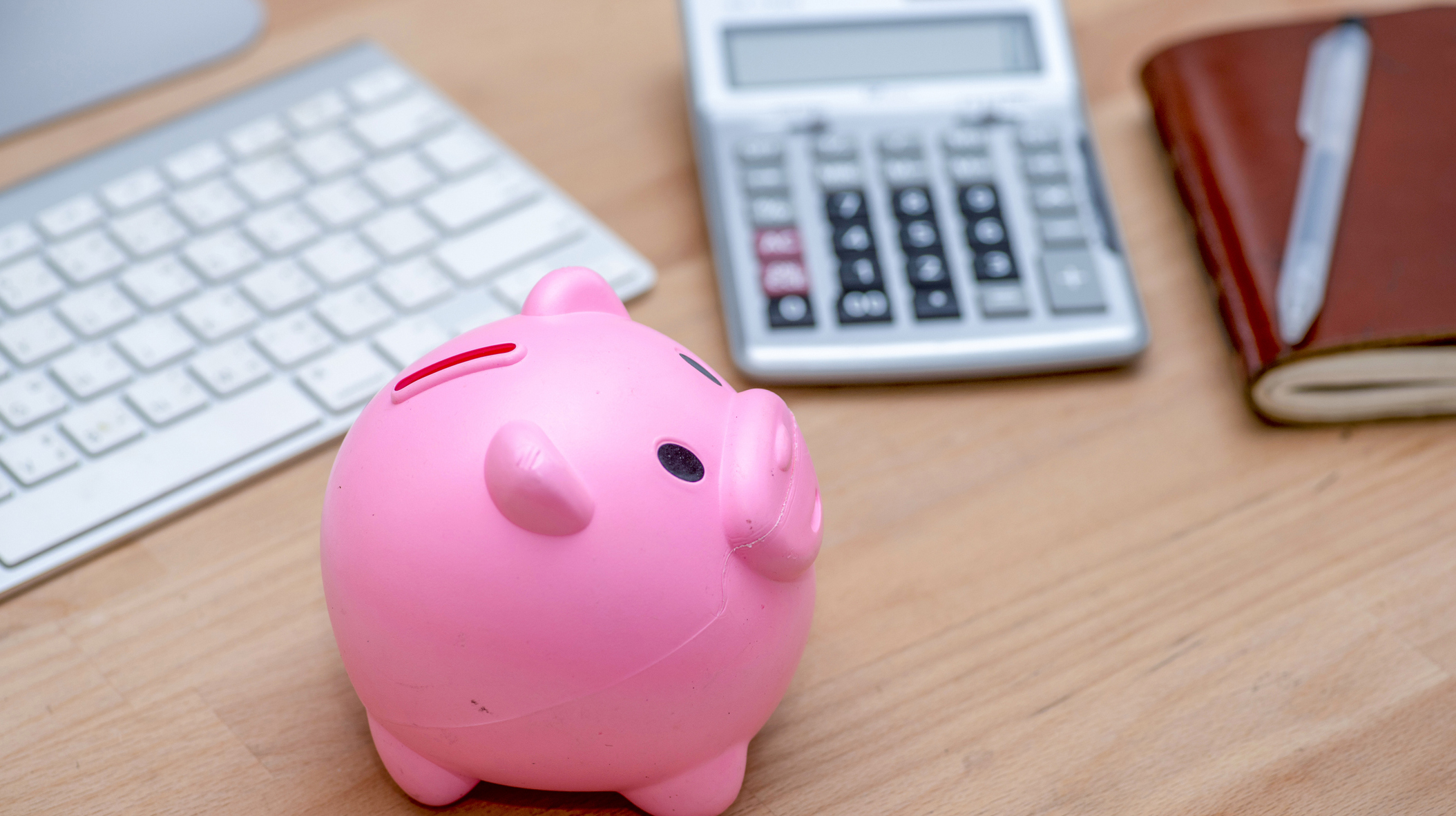 Savings and investment concept, pink piggy bank with calculator on pile or economic analysis report chart and graph on office table.