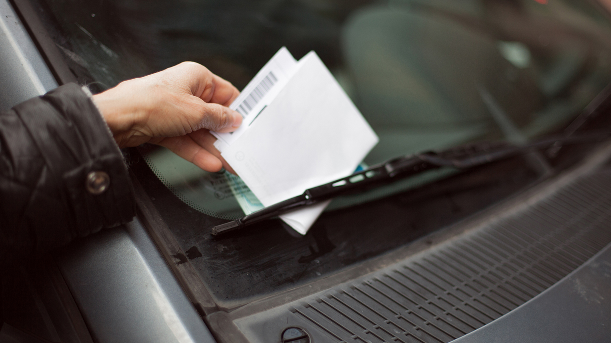 Close-up of human hand taking parking ticket from car