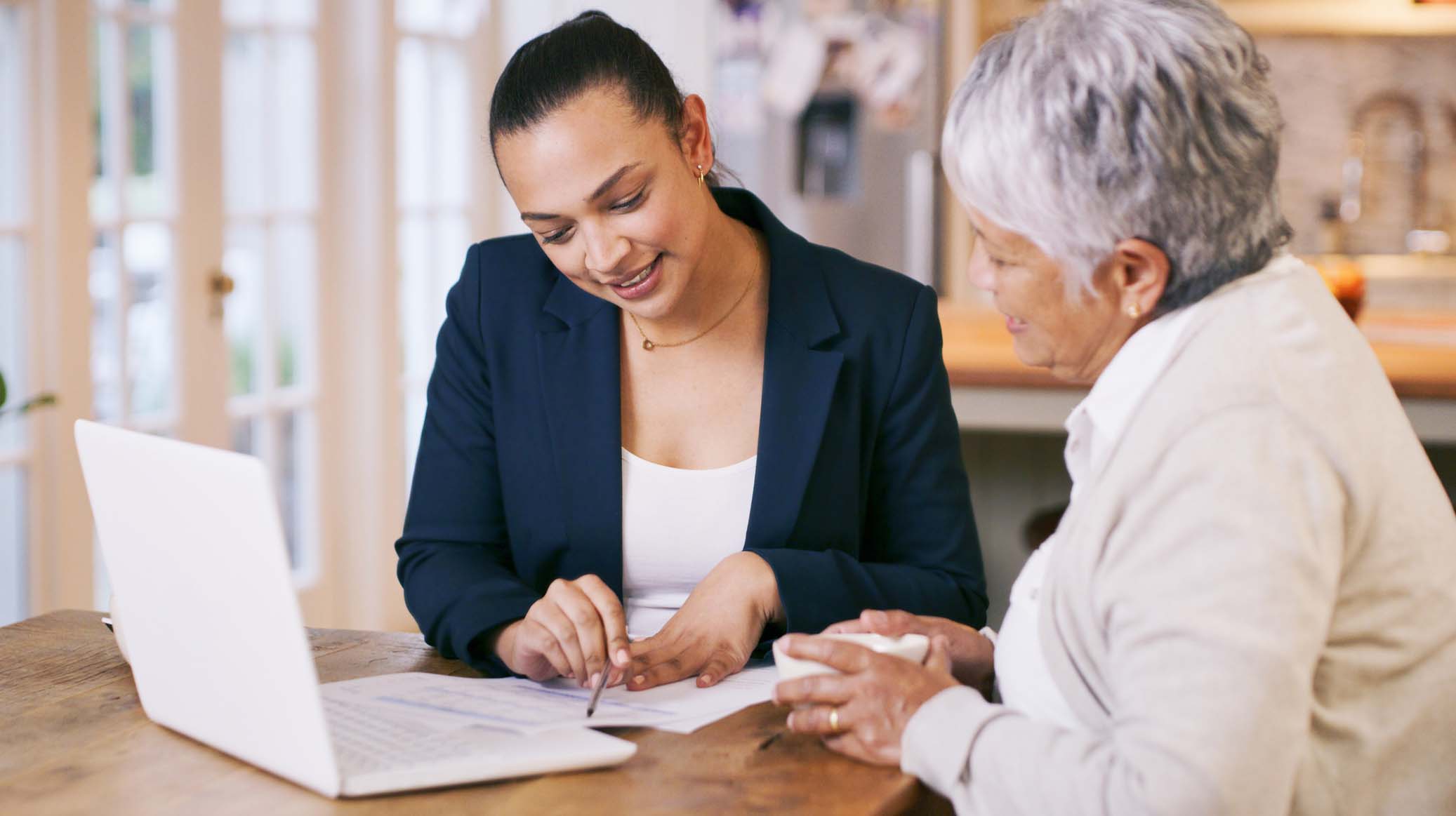 Shot of a consultant going through paperwork during a meeting with a senior woman at home